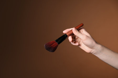Makeup artist with brush on brown background, closeup.の写真素材