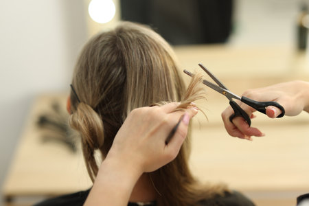 Hairdresser cutting woman's hair in salon, closeupの写真素材