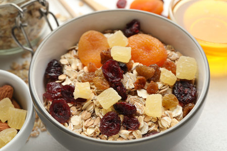 Making granola. Oat flakes, dried fruits and other ingredients on white table, closeup