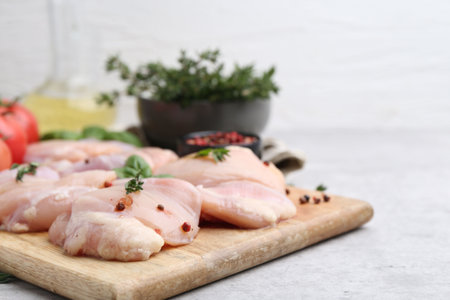 Raw chicken thighs with herbs and peppercorns on light table, closeup. Space for textの写真素材