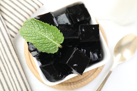 Tasty herbal jelly in bowl and mint on white table, top viewの写真素材