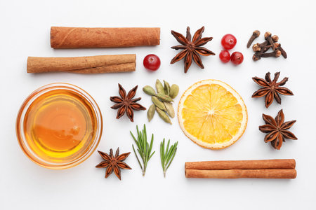 Different spices, cranberries, dry orange slice, honey and fresh rosemary for mulled wine on white table, flat layの写真素材