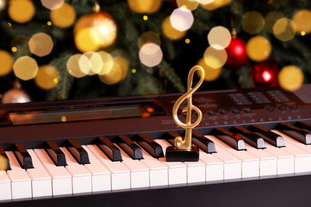 Golden treble clef and music sheets on piano near Christmas treeの写真素材