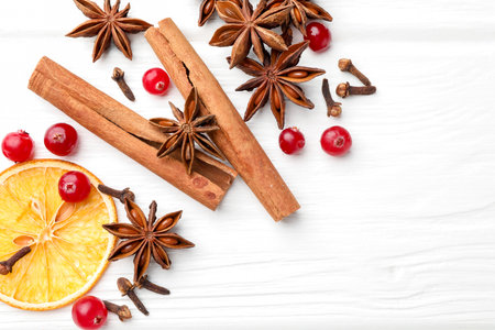 Different spices, dry orange slices and cranberries on white wooden table, flat lay. Space for textの写真素材