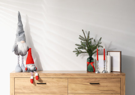Different Christmas decor on wooden cabinet near white wall indoorsの写真素材