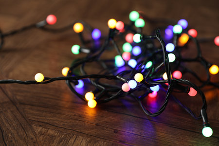 Bright Christmas lights on wooden table, closeup