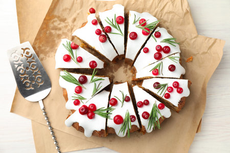 Tasty Christmas cake with cranberries and server on light wooden table, top viewの写真素材