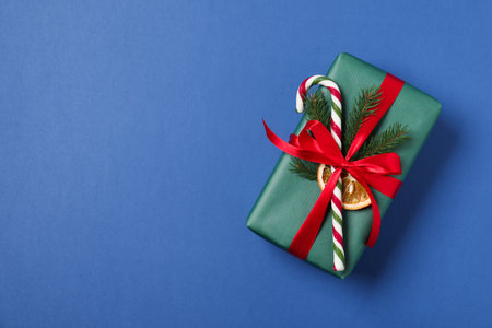 Decorated Christmas gift with candy cane on blue background, top view. Space for textの写真素材