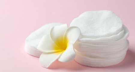 Clean cotton pads and plumeria flower on pink background, closeupの写真素材