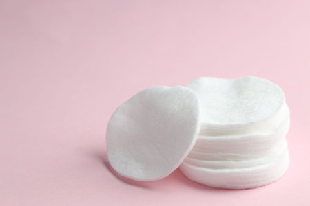 Stack of clean cotton pads on pink background, closeup. Space for textの写真素材