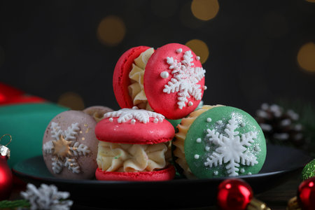 Tasty macarons and Christmas decor on black wooden table against blurred lights, closeupの写真素材