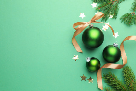 Beautiful Christmas composition with baubles, golden ribbon and confetti on green background, flat lay. Space for textの写真素材
