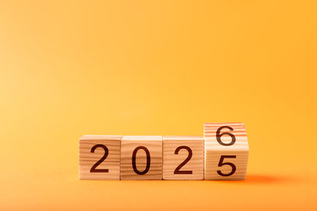 Flipping cube with number 5 and 6 to make 2026 on orange background, closeup