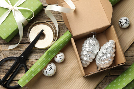 Festive packaging. Gift boxes, wrapping paper, baubles, scissors and ribbon on wooden table, flat lay. Merry Christmas and Happy New Yearの写真素材