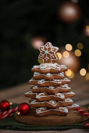 Christmas tree made of gingerbread cookies and ornaments on wooden table against blurred lights, closeupの写真素材