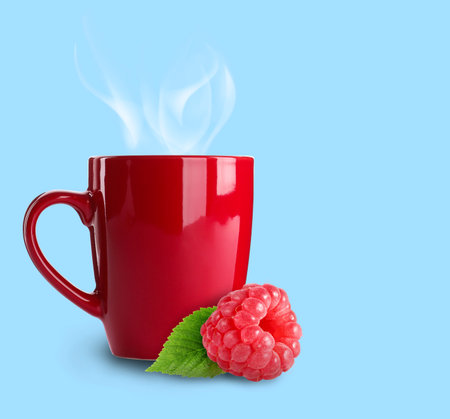 Hot beverage in cup and raspberry on light blue background. Immunity boosting drink for cold seasonの写真素材