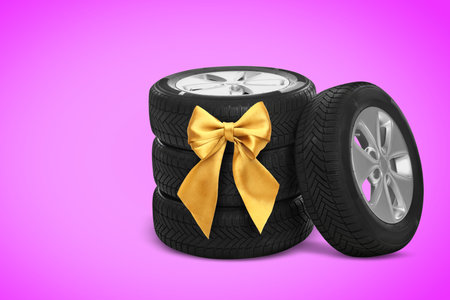 Car wheel and tires with golden ribbon bow on magenta background.の写真素材