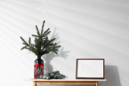 Frame and different Christmas decor on console table near white wall indoorsの写真素材