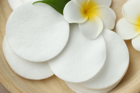 Clean cotton pads and plumeria flowers in wooden bowl, top viewの写真素材