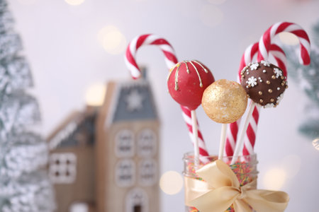 Sweet cake pops with sprinkles and candy canes in jar against light background, closeup with space for text. Christmas treatの写真素材