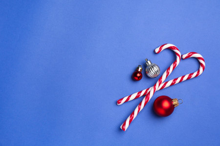 Merry Christmas and Happy New Year. Tasty candy canes and baubles on blue background, flat lay. Space for textの写真素材