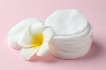 Clean cotton pads and plumeria flower on pink background, closeupの写真素材