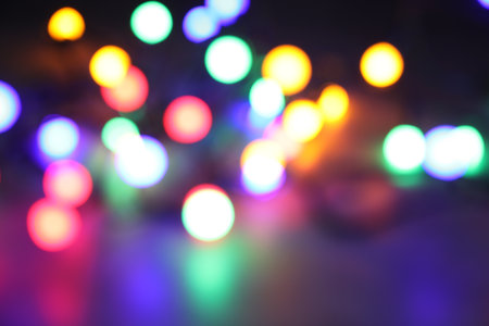 Bright Christmas lights in darkness, bokeh effect. New Year greeting card