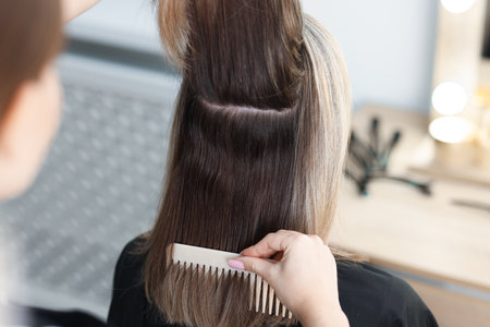 Hairdresser combing woman's hair in salon, closeup