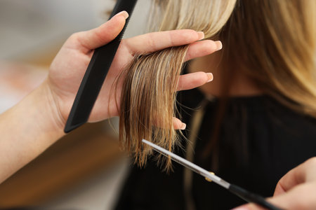 Hairdresser cutting woman's hair in salon, closeupの写真素材
