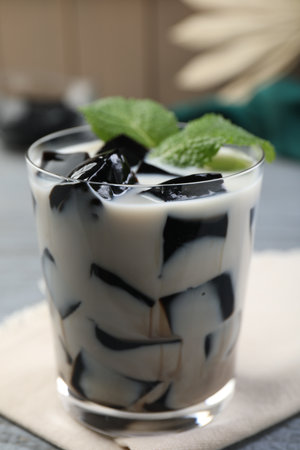 Glass of milk with tasty herbal jelly and mint on table, closeupの写真素材