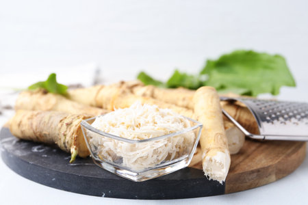 Whole and grater horseradish roots and grater on white table, closeupの写真素材
