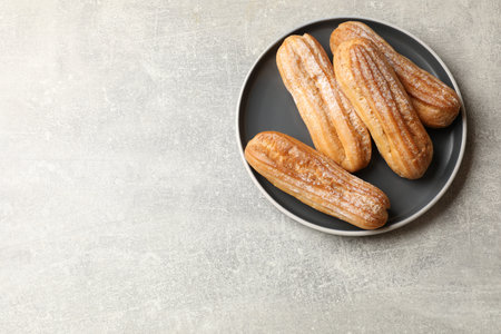 Delicious eclairs on light gray table, top view. Space for text
