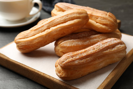 Delicious eclairs and drink on black table, closeup