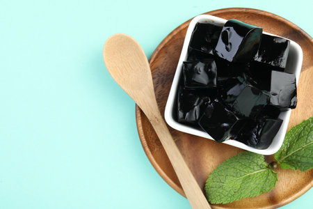 Tasty herbal jelly in bowl and mint on light blue background, top view. Space for textの写真素材