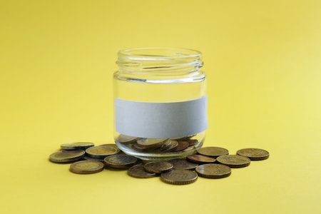 Jar with blank note and money on yellow backgroundの写真素材
