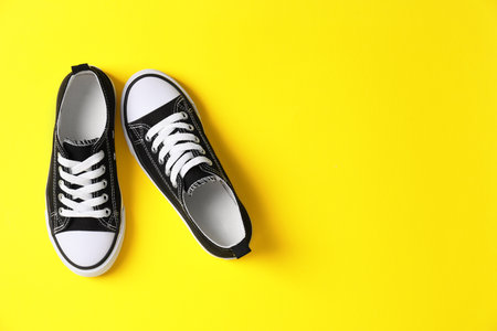 Stylish kid's sneakers on yellow background, flat lay. Space for textの写真素材