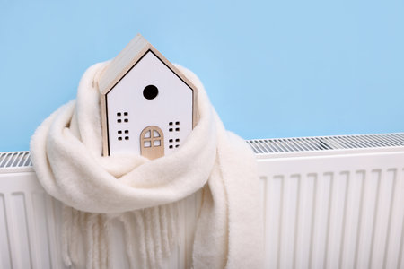 House model with scarf on heating radiator near light blue wall, closeupの写真素材