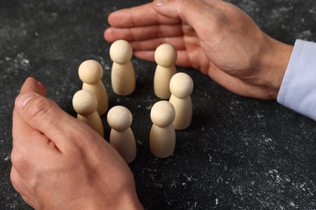 Man protecting human figures at black table, closeupの写真素材