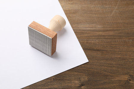One wooden stamp and blank sheet of paper on table, closeup. Space for textの写真素材