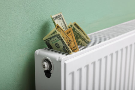 Dollar banknotes on heating radiator near green wall, closeupの写真素材