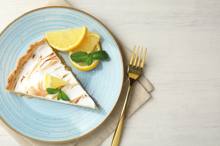 Slice of lemon meringue tart served on white wooden table, flat lay. Space for textの写真素材