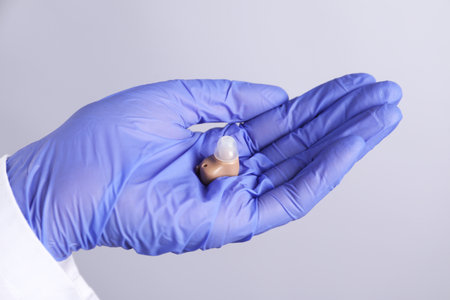 Doctor with hearing aid on light gray background, closeupの写真素材