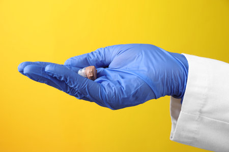 Doctor with hearing aid on yellow background, closeupの写真素材