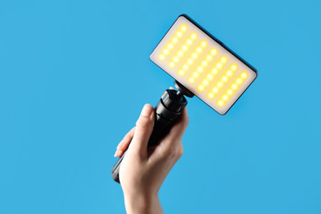 Woman with glowing LED lamp on light blue background, closeup. Space for text