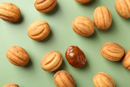 Delicious nut shaped cookies with boiled condensed milk on green background, flat layの写真素材