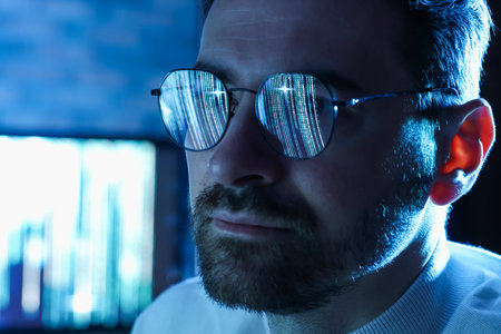 Man wearing glasses with reflection in dark room, closeup. Space for text