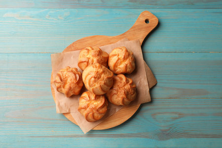 Tasty profiteroles on turquoise wooden table, top view
