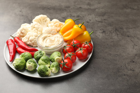 Different fresh vegetables and sauce on gray table, closeup. Space for textの写真素材