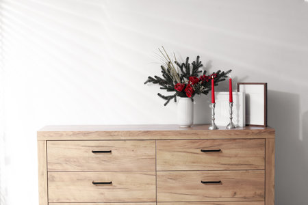 Different Christmas decor on wooden cabinet near white wall indoors, space for text