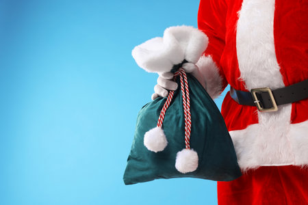 Santa Claus holding sack on light blue background, closeup with space for text. Merry Christmas and Happy New Yearの写真素材
